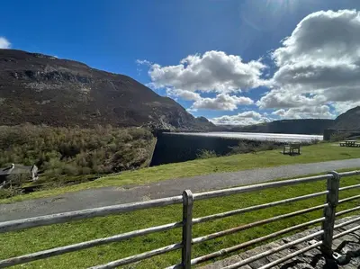 a fence on the side of a road with a reservoir at Rock Park Penthouse in Llandrindod Wells