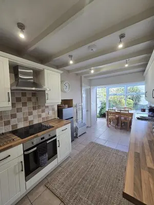 a kitchen with white cabinets and a dining room at 3 Prospect Place, New Quay, sleeps 6, parking, sea views, dog friendly in New Quay