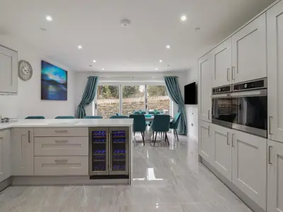 a kitchen with white cabinets and a dining room at Ty Mawr in Penrhyndeudreath