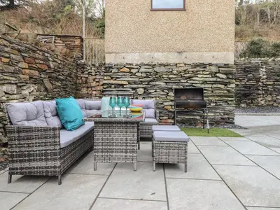 a patio with a couch and chairs and a stone wall at Ty Mawr in Penrhyndeudreath