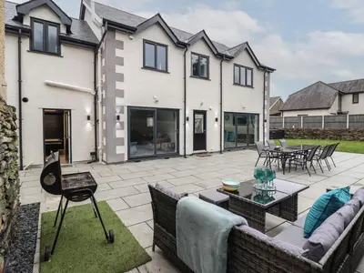 a patio with a couch and chairs in front of a house at Ty Mawr in Penrhyndeudreath