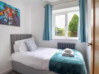 a bedroom with a bed with blue curtains and a window at Ty Mawr in Penrhyndeudreath