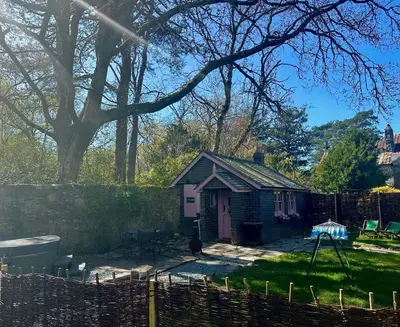 a small house with a pink door in a yard at Tiny Romantic Retreat with Hot Tub on a Country Estate near Cardigan Bay in Eryri Snowdonia in Llanbedr