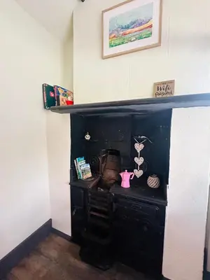a black fireplace in a room with a shelf at Tiny Romantic Retreat with Hot Tub on a Country Estate near Cardigan Bay in Eryri Snowdonia in Llanbedr
