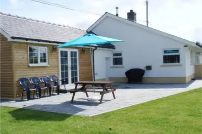 a picnic table with chairs and an umbrella in front of a house at Cottage in the Countryside Near New Quay West Wales in Llandysul