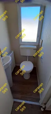 a bathroom with a toilet and a window with yellow writing at Sean's 569 cader court 045 in Talybont