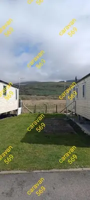 a group of yellow signs on the grass next to a trailer at Sean's 569 cader court 045 in Talybont