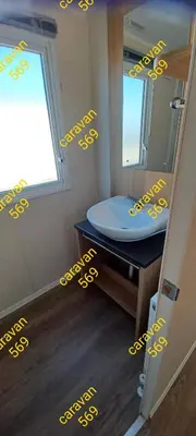 a bathroom with a sink and a mirror with yellow writing at Sean's 569 cader court 045 in Talybont