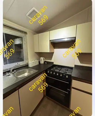 a kitchen with a stove and a sink with yellow letters at Sean's 569 cader court 045 in Talybont