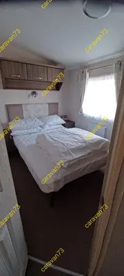 a bedroom with a large bed and a window at Caravan 73 snowdon summit 013 in Talybont