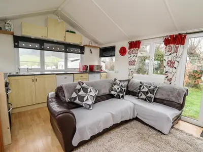 a living room with a couch and some windows at Chalet 32 in Aberystwyth