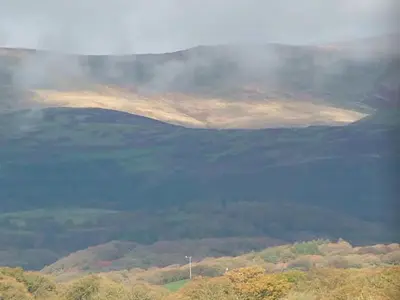 a misty view of a mountain with a body of water at Stunning views of Ynyshir & Southern Snowdonia in Machynlleth