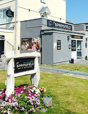 a park bench with flowers in front of a building at The Springfield Hotel in Fairbourne