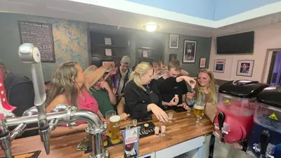 a group of people standing around a bar at The Springfield Hotel in Fairbourne
