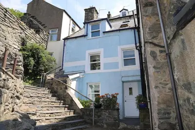a blue house with stairs in front of it at Hen Blas, 14th century 2 bedroom Cottage in Barmouth
