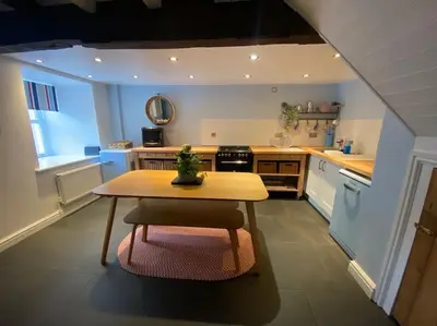 a kitchen with a wooden table and a table sidx sidx sidx sidx at Hen Blas, 14th century 2 bedroom Cottage in Barmouth