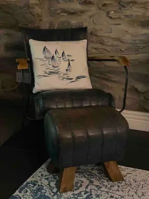a leather chair with a pillow in a room at Hen Blas, 14th century 2 bedroom Cottage in Barmouth