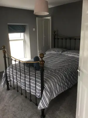 a bedroom with a bed with a striped comforter and a window at Harbour House in Barmouth