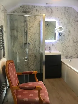 a bathroom with a chair and a shower and a sink at Harbour House in Barmouth