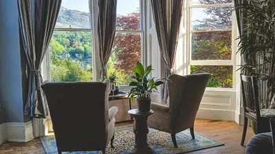 a living room with two chairs and a large window at Amazing Cader views Torrent en suite in Dolgellau