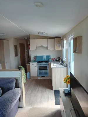 a small kitchen with a stove and a couch at 2 Bed Chalet - Sleeps 4 - Pets - Parking in New Quay