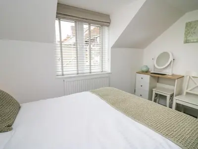a white bedroom with a bed and a mirror at 2 Penporth in Rhayader