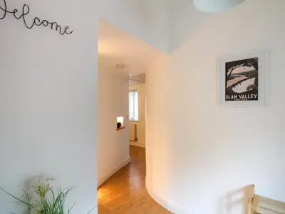 a room with a white wall with a picture on the wall at 1 Penporth in Rhayader