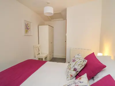 a bedroom with a white bed with purple sheets and a chair at 1 Penporth in Rhayader