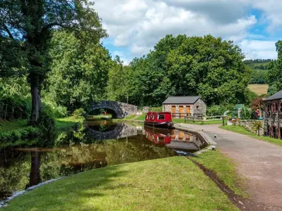 a small boat in a river with a bridge at 1 Bed in Talybont-on-Usk oc-a29348 in Talybont