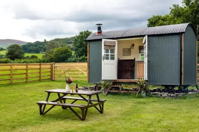a picnic table in front of a green trailer at 1 Bed in Talybont-on-Usk oc-a29348 in Talybont