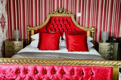 a bedroom with a red bed with red pillows at The Hotel Commodore in Llandrindod Wells