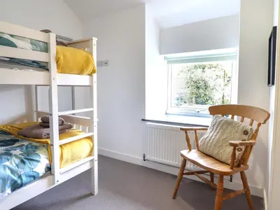a bedroom with bunk beds and a chair and a window at Ty Dyffryn in Blaenau-Ffestiniog