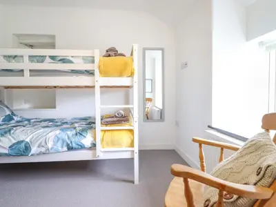 a bedroom with two bunk beds and a chair at Ty Dyffryn in Blaenau-Ffestiniog