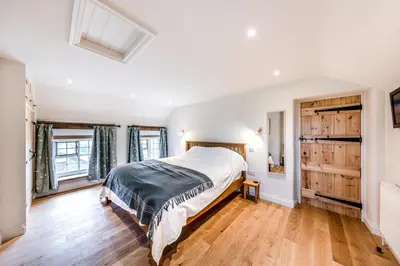 a bedroom with a large bed and wooden floors at 4 Bed in Derwenlas oc-c29244 in Machynlleth