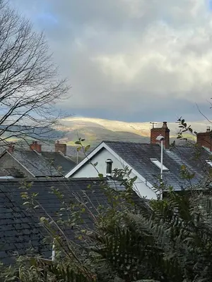 a roof of a house with mountains in the background at Poets Cottage Eglwys Fach in Scyborycoed