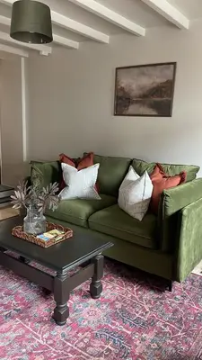 a green couch in a living room with a coffee table at Poets Cottage Eglwys Fach in Scyborycoed