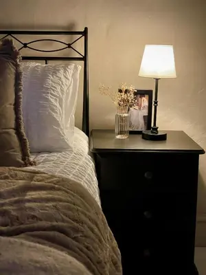 a bed with a night stand with a lamp on it at Poets Cottage Eglwys Fach in Scyborycoed