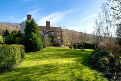 a large house on a green lawn with trees and bushes at The Manor House in Church Stretton