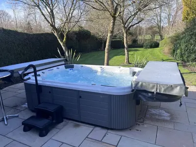 a hot tub sitting on a patio with a table at The Manor House in Church Stretton