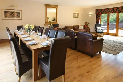 a dining room with a long table and leather chairs at Toad Hall in Church Stretton