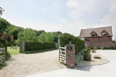 a house with a fence and a clock in the yard at Toad Hall in Church Stretton