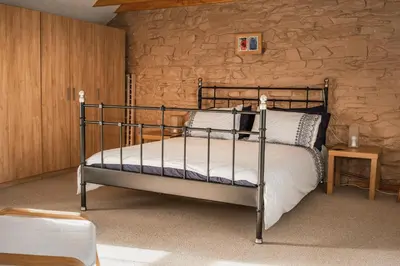 a bedroom with a bed and a stone wall at Horseshoe Cottage Aberaeron in Ciliau-Aeron