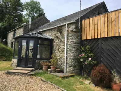 an extension to a stone cottage with a black house at Horseshoe Cottage Aberaeron in Ciliau-Aeron