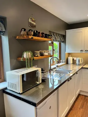 a kitchen counter with a microwave and a sink at Lilac Cottage in Stoke Prior