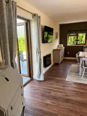 a living room with a fireplace and a sliding glass door at Lilac Cottage in Stoke Prior