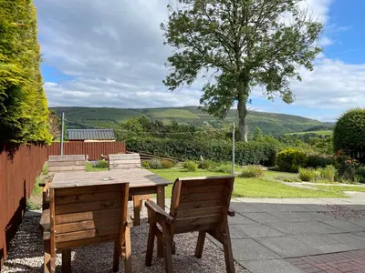a wooden table and chairs with a view of the hills at Ty Ray Penmaes in Rhayader