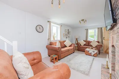 a living room with two couches and a tv at Mill Cottages Shrewsbury With Hottub in Merrington