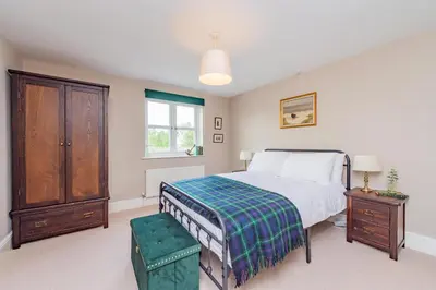 a bedroom with a bed and a dresser and a window at Mill Cottages Shrewsbury With Hottub in Merrington