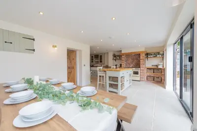 a dining room with a table with white dishes on it at Mill Cottages Shrewsbury With Hottub in Merrington
