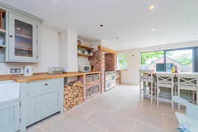 a kitchen with white cabinets and a counter with fire wood at Mill Cottages Shrewsbury With Hottub in Merrington